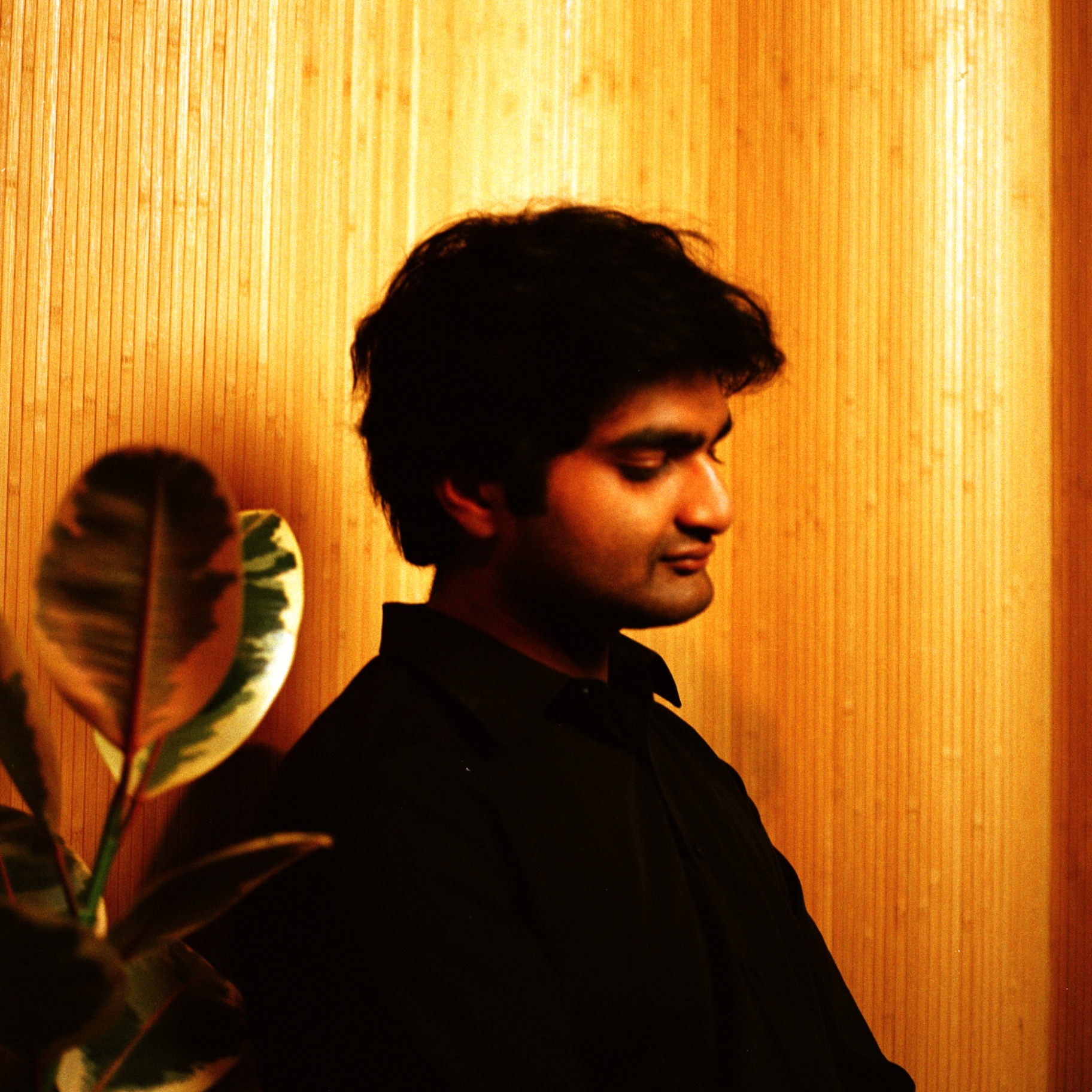 Eshan Agarwal in profile against a warm wooden wall