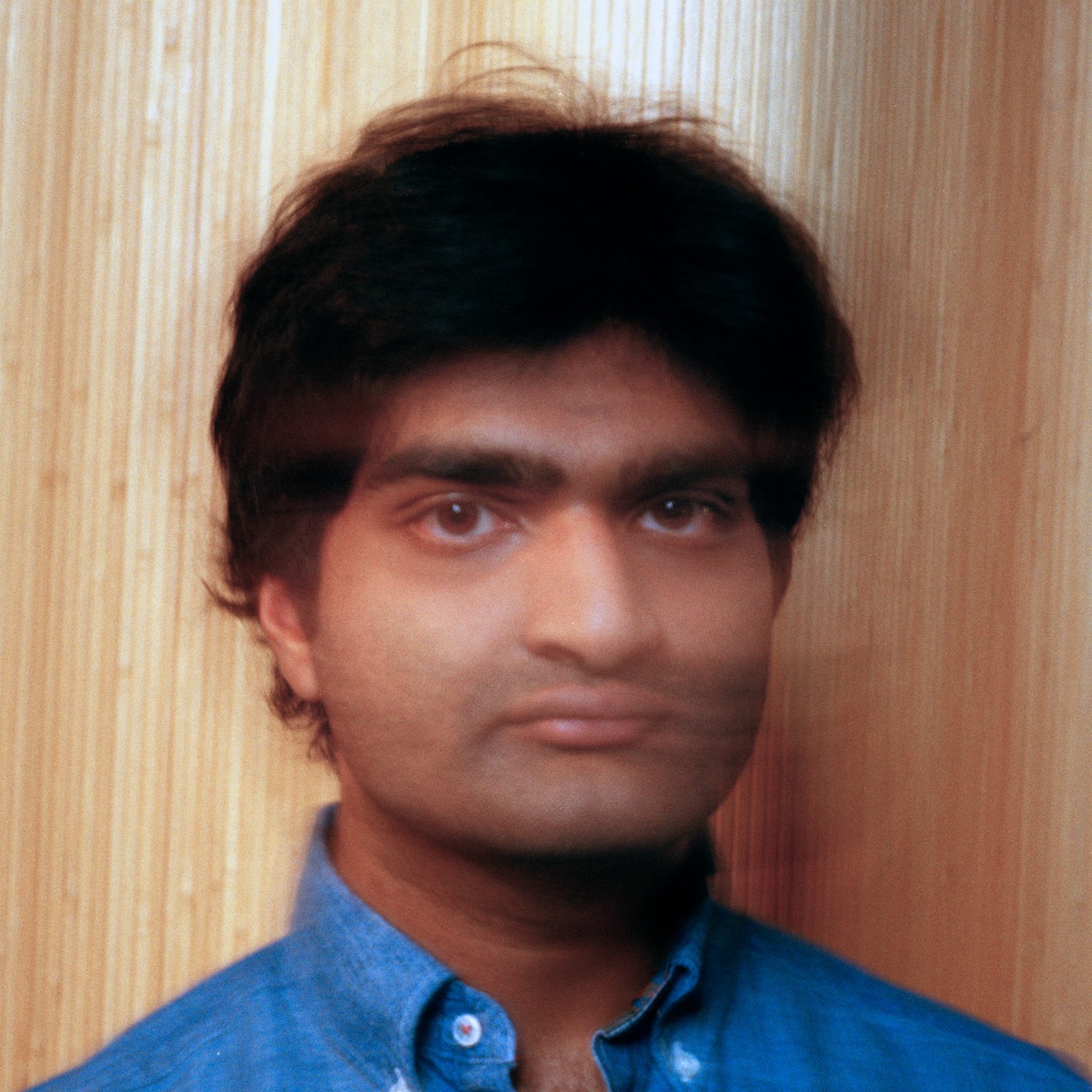 Eshan Agarwal straight-on portrait against wooden panels